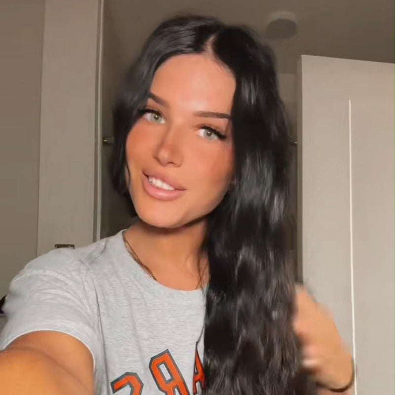 Woman holding a long hair extension in a room with a door in the background